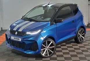 Vue 3/4 avant droite d'une Aixam Ambition bleu avec bandes grises sur le capot et jantes noires à rayures argentées.