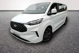Ford Tourneo Custom blanc en 3/4 avant droit, avec calandre noire et jantes foncées visibles sur sol gris.