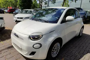 Vue 3/4 avant droite d'une Fiat 500 électrique blanche, avec logo distinctif et jantes multibranches visibles.