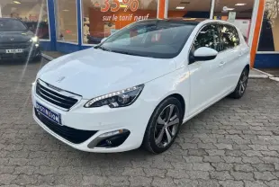 Peugeot 308 blanche vue 3/4 avant droit, toit panoramique en verre et jantes alliage distinctives visibles.