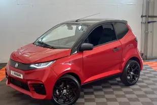 Vue 3/4 avant droite d'une Aixam Ambition 0.5 City Sport rouge avec toit noir et jantes noires brillantes.