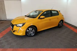 Peugeot 208 jaune vue 3/4 avant droit dans un garage, avec feux LED et jantes alliage noires.