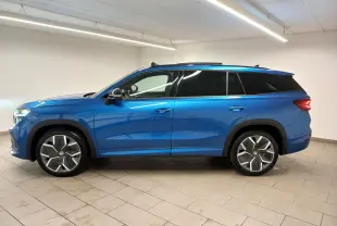 Vue de profil côté gauche d'un Skoda Kodiaq 2024 bleu RS avec jantes alliage 20'' Rila anthracite et toit panoramique.