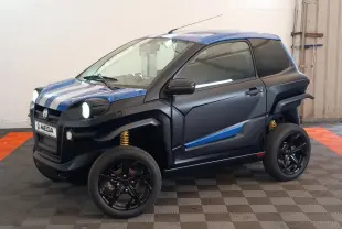 Vue 3/4 avant droite de l'AIXAM MEGA E-SCOUTY EVO bleu avec bandes blanches, jantes noires et suspensions jaunes visibles.