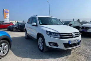 Volkswagen Tiguan blanc vu en 3/4 avant droit sur parking avec jantes alliage et calandre noire chromée.