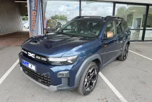 Vue 3/4 avant droite du Dacia Bigster Hybrid 155 Extreme bleu indigo avec jantes alliage noires et rétroviseurs bronze.