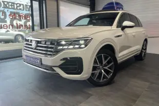 Vue 3/4 avant droite d'un Volkswagen Touareg blanc avec jantes alliage 20 pouces et calandre chromée R-Line.