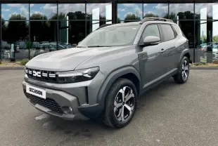 Dacia Duster Journey Hybrid 140 gris clair en 3/4 avant droit, avec calandre distinctive et jantes modernes.