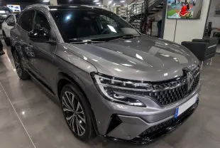 Renault Austral E-Tech gris schiste en 3/4 avant droit, avec calandre noire à damier et jantes bicolores.