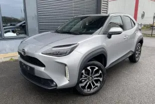 Toyota Yaris Cross gris clair vue 3/4 avant droit, avec phares LED et jantes alliage noires et argentées.