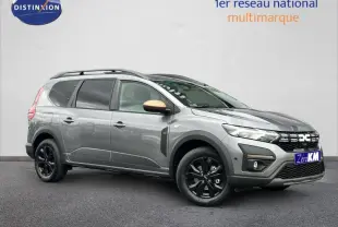 Vue 3/4 avant droit du Dacia Jogger gris schiste métallisé avec jantes noires et barres de toit visibles.