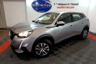Peugeot 2008 BlueHDi 110 gris clair vue 3/4 avant droit avec phares allumés en intérieur showroom