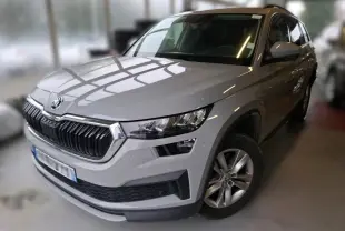 Vue 3/4 avant droit d'un Skoda Kodiaq gris clair 2023, mettant en valeur sa calandre distinctive et ses phares modernes.