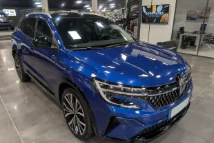 Renault Austral E-Tech Hybrid bleu Iron en 3/4 avant droit, mettant en valeur sa calandre et ses jantes bicolores.