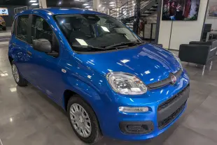 Vue 3/4 avant droite d'une Fiat Panda 1.0 Hybrid City 2025 en Bleu Italia dans un showroom moderne.