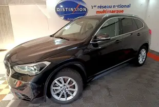 BMW X1 sDrive20i noir vue 3/4 avant droit en intérieur avec jantes alliage et phares LED allumés