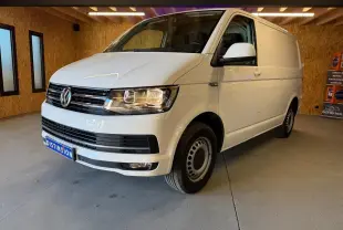 Vue 3/4 avant droit d’un Volkswagen Transporter blanc, fourgon utilitaire avec jantes tôles et calandre noire.