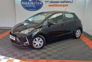 Toyota Yaris 1.5 VVT-I Hybrid noire vue de profil avant droit en intérieur sur sol damier gris et orange.