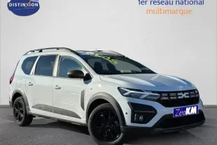 Dacia Jogger blanc glacier en 3/4 avant droit avec jantes noires et barres de toit visibles.