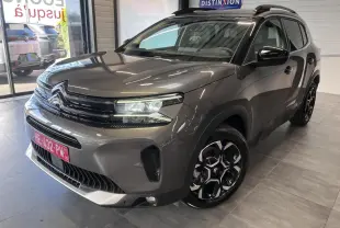 Vue 3/4 avant droite du Citroën C5 Aircross gris platinium avec jantes alliage bi-ton et barres de toit noires.