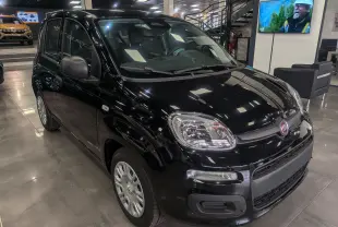 Vue 3/4 avant droite d'une Fiat Panda 2025 noire, compacte et brillante, exposée en showroom moderne.