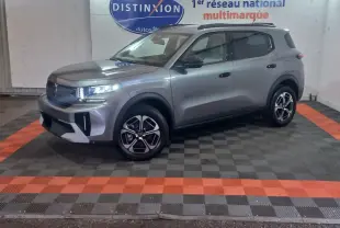 Vue 3/4 avant droit d'un SUV Citroën C3 gris foncé avec jantes noires et détails modernes sur fond intérieur showroom.