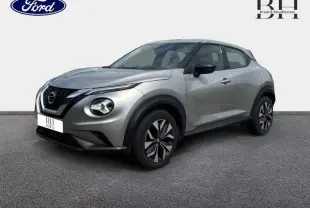 Nissan Juke 2023 gris perle métallisé vu en 3/4 avant droit, avec phares ronds et jantes au design moderne.