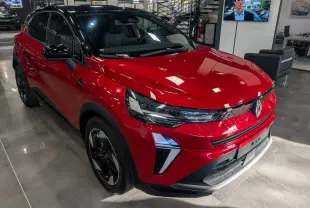 Vue 3/4 avant gauche du Renault Captur E-TECH rouge Flamme avec toit noir et jantes noires en showroom.