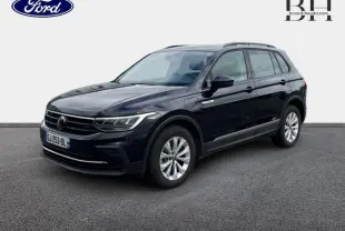 Volkswagen Tiguan 1.4 eHybrid noir nacré en 3/4 avant droit, avec jantes alu et barres de toit visibles.