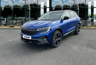 Renault Austral bleu en 3/4 avant droit, avec jantes noires et calandre moderne devant un bâtiment vitré.