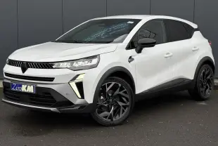 Renault Captur blanc nacré en 3/4 avant droit, avec jantes noires et détails noirs contrastants.