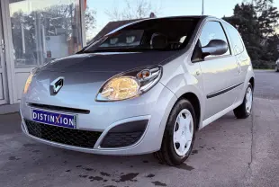 Renault Twingo II gris vue 3/4 avant droit avec phares allumés et jantes tôles blanches.