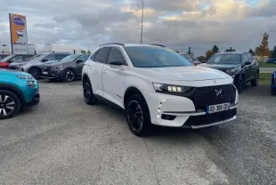 DS7 Crossback blanc en 3/4 avant droit avec calandre noire et jantes noires sur parking extérieur.