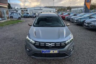 Vue avant d'un Dacia Jogger gris métallisé avec calandre noire et feux LED allumés sur un parking extérieur.