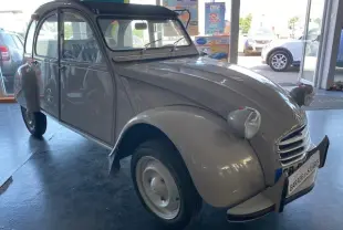 Citroën 2 CV beige clair refaite à neuf vue 3/4 avant gauche dans un garage lumineux.