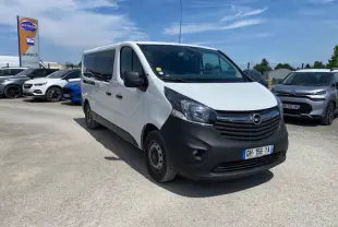 Opel Vivaro blanc vu en 3/4 avant droit, avec calandre noire et pare-chocs avant mat, stationné en extérieur.