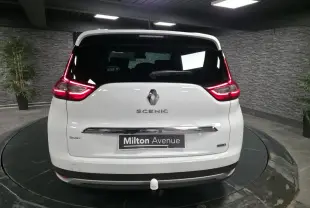 Vue arrière d'un Renault Scénic blanc nacré de 2017 avec hayon chromé et attelage visible en intérieur showroom.