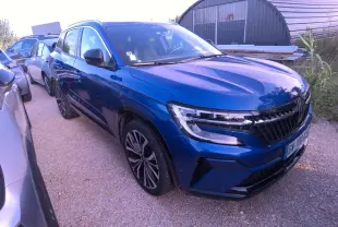 Renault Austral bleu métal foncé vu en 3/4 avant droit avec calandre damier et jantes alliage 20 pouces.