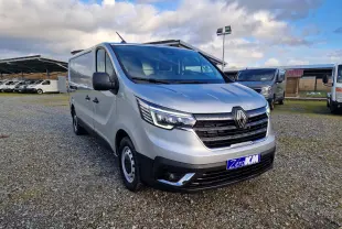 Renault Trafic Fourgon gris Highland en 3/4 avant droit, avec calandre noire et feux LED allumés.