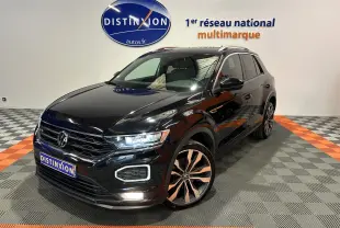 Volkswagen T-Roc noir en 3/4 avant droit, avec jantes alliage bicolores et feux LED allumés en intérieur showroom.