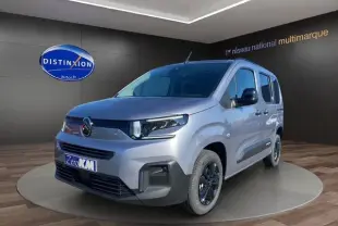 Vue 3/4 avant d'un Citroën Berlingo gris Artense avec jantes alliage noires et calandre moderne en showroom.