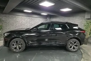 Profil côté gauche du CUPRA Formentor noir brillant avec jantes alliage et toit ouvrant panoramique en intérieur showroom.