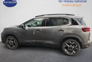Citroën C5 Aircross Hybrid gris platinium en 3/4 avant droit avec jantes bicolores et barres de toit noires.