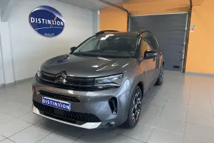 Vue 3/4 avant d'un Citroën C5 Aircross hybride gris platinium avec jantes biton et toit noir en showroom.