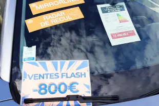 Vue avant rapprochée du pare-brise gris Artense d’un Peugeot 2008 2020 avec affiches promotionnelles et étiquettes techniques.