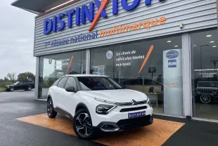 Citroën C4 blanc en 3/4 avant droit, avec jantes noires et toit noir, devant une concession Distinxion.