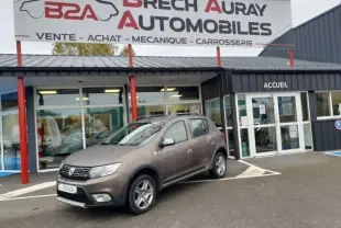 Vue 3/4 avant gauche d'une Dacia Sandero Stepway 2017 brun tourmaline devant un garage Brech Auray Automobiles.