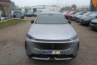Vue avant d'un Peugeot 5008 gris Artense 2025 avec calandre noire et logo lion central sous la pluie.