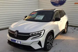 Renault Austral E-Tech Full Hybrid 200 Iconic blanc nacré avec toit noir, vue 3/4 avant sur sol mouillé