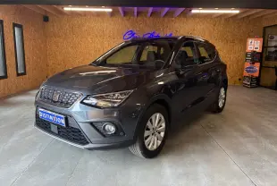 SEAT Arona gris foncé en 3/4 avant droit dans un showroom avec éclairage intérieur et jantes argentées.